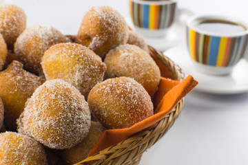 Traditional Brazilian mini fried cakes called bolinho de chuva in a basket in white breakfast table background close