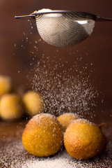 Traditional Brazilian mini fried cake called bolinho de chuva with falling sugar in wood background
