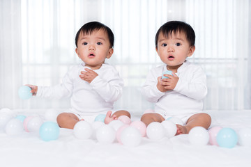 cheerful twin babies playing color ball on  bed