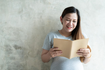 Asian pregnant woman reading a book in the living close up.  Portrait Photograph with copy sapce.