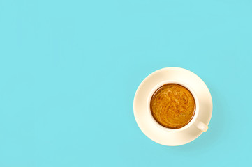 Cup of coffee on blue background. Top view