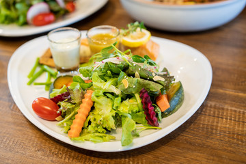 Smoked salmon salad with cream, spicy and Japanese sauce served on wooden table in the restaurant.