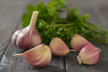 Large fresh garlic with parsley leaves on a wooden table. Component of traditional medicine.