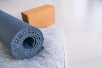 Yoga mat, cork block and linen meditation cushion. Natural organic material props for wellness studio on wooden floor background. Eco-friendly sustainable products for wellness and fitness.