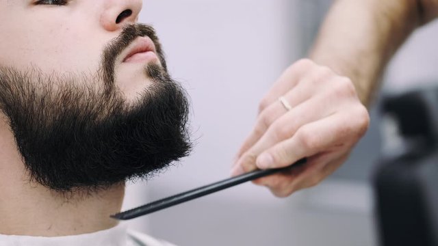 professional businessman getting his beard froomed and trimmed by a barber