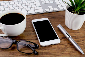 Wooden table office desk with computer,keyboard,smart phone and cup of coffee