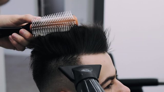 attractive man getting his hair slyled and blow dried after a haircut