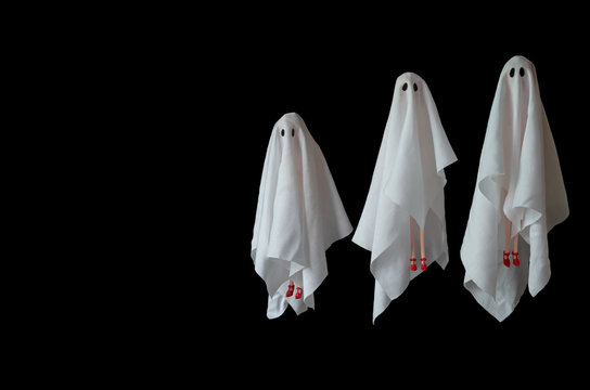 A group of female ghost white sheet costume flying in the air with black background. Minimal Halloween scary concept.