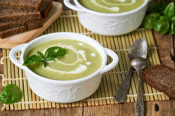 Zucchini cream soup with basil in white bowls 