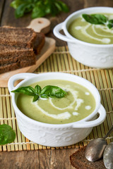 Zucchini cream soup with basil in white bowls 