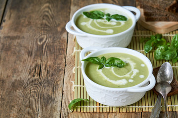Zucchini cream soup with basil in white bowls 