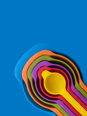 Measuring spoon set made of colorful plastic on a blue background, kitchen equipment. Group of...