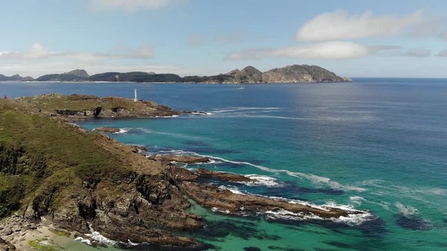 Beautiful aerial footage of Cies Islands from Costa da Vela on a sunny morning after the fog lifted. A fishing boat sails at the distance. Transparent greenish water at the foot of the cliffs.