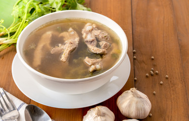 Top view of pork bone soup in white bowl on wooden table.
