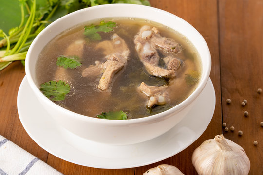 Top view of pork bone soup in white bowl on wooden table.