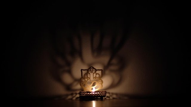Shadow and light dance, play reflection on wall of Ganesha cutout, also Ganapati Vinayaka, one of the best-known and most worshipped deities in the Hindu pantheon, specially during Diwali 