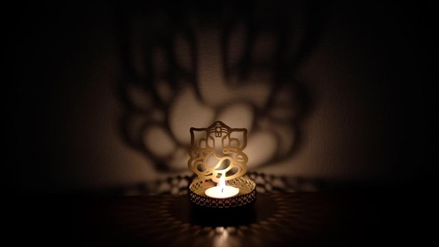 Static shadow and light dance, play reflection on wall of Ganesha cutout, also Ganapati Vinayaka, one of the best-known and most worshipped deities in the Hindu pantheon, specially during Diwali 