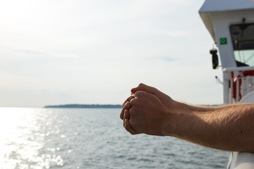 Hands against the faint background of the island of Ven in southern Sweden while taking the ferry...