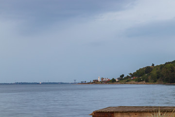 Haken lighthouse on the island of Ven in southern Sweden with Landskrona town visible in the background seen from the camping on the island at sunset in summer. 