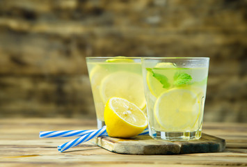 Lemonade or mojito cocktail with lemon and mint on wood background