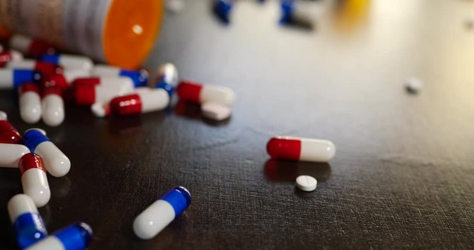 A drug addict pouring out prescription painkiller pills, narcotics and medicine in a frantic search to get high.