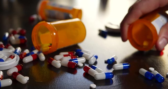 A drug addict pouring out prescription painkillers, narcotics and medicine in a frantic search to get high.