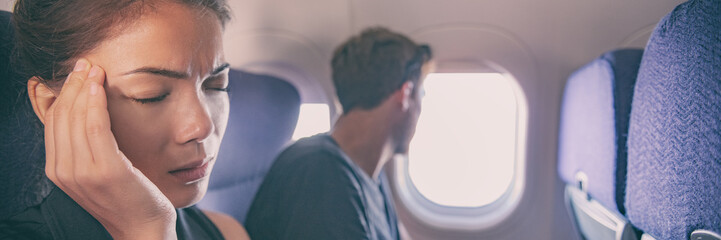 Sick fear of flying inside plane cabin woman in airplane with headache panoramic banner. Asian passenger on travel feeling sick with stress anxiety migraine. Couple tourists.