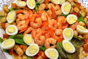 Dish with peeled shrimps, quail eggs and crackers, close-up