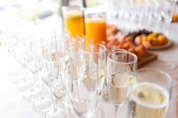 reception. Table top full of glasses of sparkling white wine with canapes and antipasti in the background. champagne bubbles