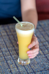 Woman hand holding a glass of fresh pineapple juice, close up