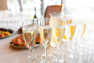 reception. Table top full of glasses of sparkling white wine with canapes and antipasti in the background. champagne bubbles