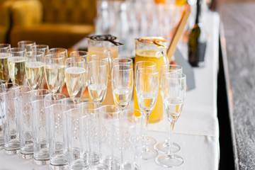 reception. Table top full of glasses of sparkling white wine with canapes and antipasti in the background. champagne bubbles