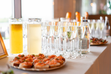 reception. Table top full of glasses of sparkling white wine with canapes and antipasti in the background. champagne bubbles