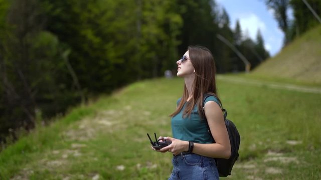 Young woman holding controller for drone operation turns to camera