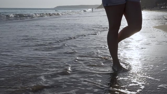 Young female walking on the beach at sunset