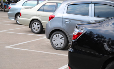 Closeup of rear or back side of black car and other cars parking in parking area.