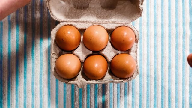 Egg carton stop motion hands opening box. Eggs cracked & empty then reversed to whole egg & box closed.