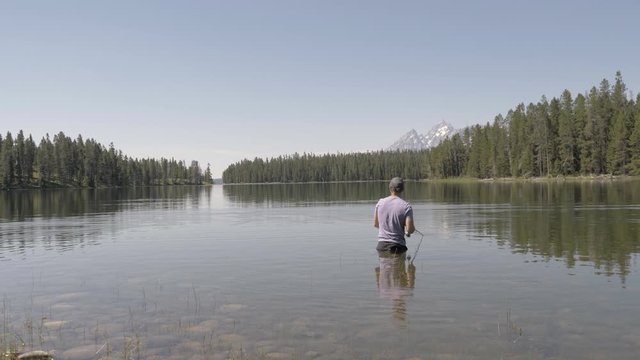 Man fishing on lake in the Grand Tetons National Park 4k