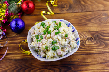 Traditional Russian festive salad Olivier and New Years decorations on wooden table