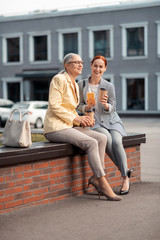 Obraz premium Two modern women sitting on the bench outdoors
