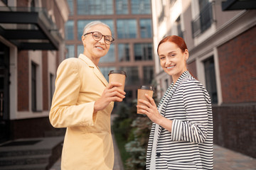 Contented colleagues smiling with paper cups of coffee