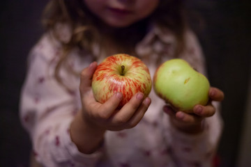 GIRL eats ripe apples. A child is eating an apple. Useful food fruits. Apples in the hands of a child.