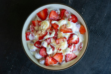 Red strawberry and white yogurt brulee. Fruit dessert on breakfast with wedges of perfectly ripe in season strawberry, closeup