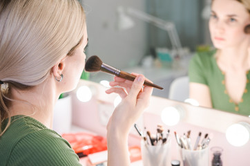Beautiful blonde woman near mirror in make-up room