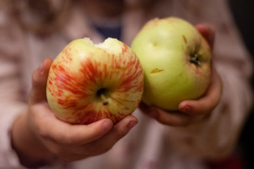 GIRL eats ripe apples. A child is eating an apple. Useful food fruits. Apples in the hands of a child.