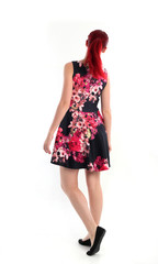 full length portrait of red haired girl wearing a cute flower patterned dress. Standing pose against a  white studio background.