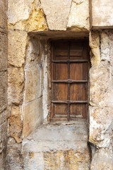 Fototapeta na wymiar Wooden grunge closed window with wrought iron grid in stone bricks wall, Old Cairo, Egypt