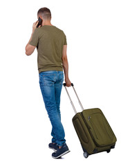 Back view of walking man with suitcase talking on the smartphone.