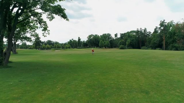 Aerial view of man, who using a VR headset and playing a virtual game in the park. Young guy in helmet experiencing augmented reality on the background of nature. 4K drone footage.