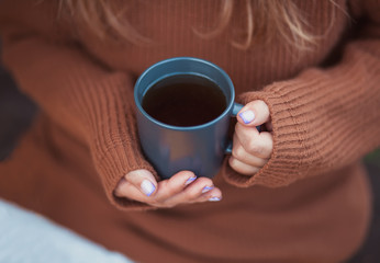Outdoors autumn picnic. Young girl holding mug of hot coffee in a hand